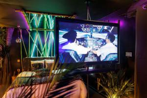 a television with two men on it in a room at Cupidon LoveRoom Suite Amazone in Vesoul