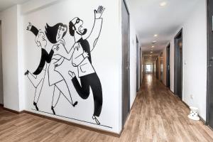 a wall mural of three women dancing in a hallway at Hotel O Noida premium inn in Noida