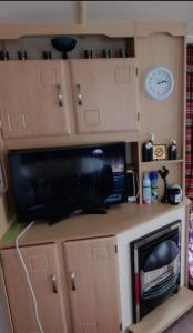 - une télévision au-dessus d'un bureau avec un four micro-ondes dans l'établissement Mv16 4 bed caravan on the Golden Palm, à Chapel St. Leonards