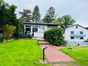 a house with a brick walkway in front of a yard at Ferienhaus Hugo in Lubmin +6 photos