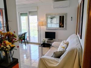 ein Wohnzimmer mit Couch und Fernseher in der Unterkunft Ada Neptuno Apartamento, Aire acondicionado, WiFi, Piscinas, Parking in Peñíscola