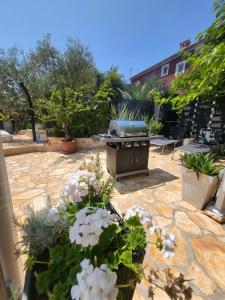 a patio with a grill and flowers in a yard at Villa AMore Radini with a private heated saltwater pool and private parking in Brtonigla