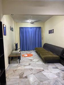 a living room with a bed and a blue curtain at Seri Laguna Homestay in Port Dickson