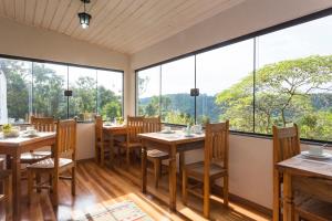 um restaurante com mesas e cadeiras e janelas grandes em Pousada Villa Hegus em Campos do Jordão