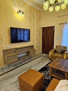 Una sala de estar con un televisor de pantalla plana en la pared. en Elegant Villa in Heart of Dehradun - Boutique Homestay, en Dehradun