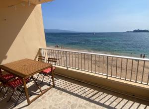 een tafel en stoelen op een balkon met uitzicht op het strand bij Appartement pieds dans l eau in Ajaccio