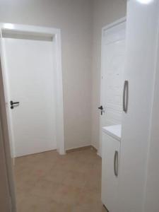 een witte kamer met twee witte kasten en een koelkast bij Oasis Villa in Shtoji i Ri