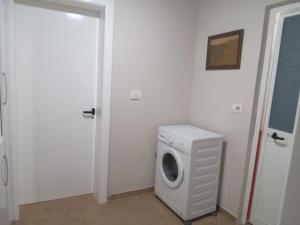 een wasmachine in een witte kamer met een deur bij Oasis Villa in Shtoji i Ri