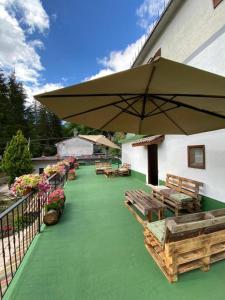 Un patio con bancos y una gran sombrilla. en Claudia B&B, en Pescasseroli