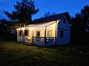 a white tiny house with lights on it at night at Sosny i Róże in Domysłów +4 photos