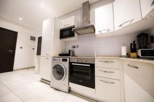 アクラにあるThe Signature Apartment Unit A407-Charming stay in Accra with AC, Free WiFiの白いキッチン(洗濯機付)