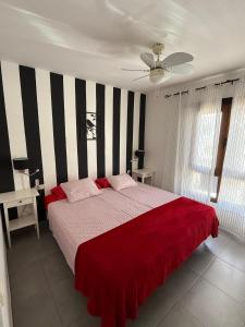 une chambre avec un grand lit recouvert d'une couverture rouge dans l'établissement Aloha Corralejo, à Corralejo 38 autres photos