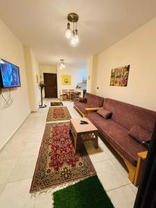 a living room with a couch and a rug at شاليه عائلي في قرية جراند هيلز طابق أرضي بحديقة خاصة غرفتين نوم وريسبشن واسع in Dawwār ‘Abd Allāh