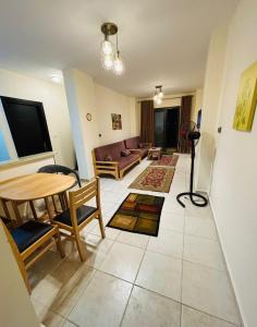 a living room with a table and a couch at شاليه عائلي في قرية جراند هيلز طابق أرضي بحديقة خاصة غرفتين نوم وريسبشن واسع in Dawwār ‘Abd Allāh