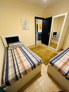 a bedroom with two beds and a mirror at شاليه عائلي في قرية جراند هيلز طابق أرضي بحديقة خاصة غرفتين نوم وريسبشن واسع in Dawwār ‘Abd Allāh +28 photos