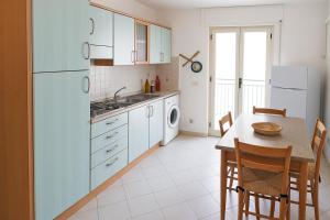 a kitchen with a table and a white refrigerator at Appartamenti ABR Corso in Le Castella