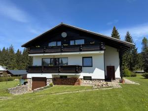 een groot wit huis met een zwart dak bij Pension Burger in Harrachov