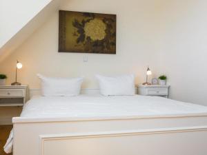 a bedroom with a large white bed with two night stands at Ostertresker 78, DHH in Tinnum