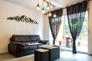 a living room with a leather couch and a table at Appartement Neuf à 50 m du Télécabine Prorel 4 personnes box ski et garage privé in Briançon
