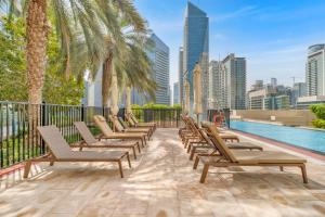 Una fila de tumbonas junto a una piscina. en Dubai Marina Promenade 1BR Apartment with Pool near JBR, en Dubái
