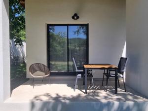 a dining room table and chairs in front of a window at Gîtes Boisé en Cévennes - Ô Jardin d'À Côté in Avèze