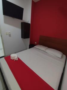 a bedroom with a white bed with a red wall at Hotel Madeleine Inn Sede Sur in Barranquilla +2 photos