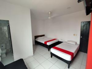 two beds in a white room with a bathroom at Hotel Madeleine Inn Sede Sur in Barranquilla