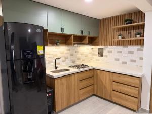 a kitchen with a black refrigerator and a sink at APTO LODGE - Confortable y acogedor apartamento al norte de Barranquilla vía a Puerto Colombia in Barranquilla