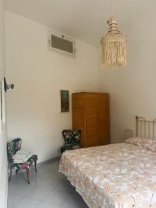una camera con un letto e due sedie e un lampadario a braccio di FM Apartaments Forio a Ischia