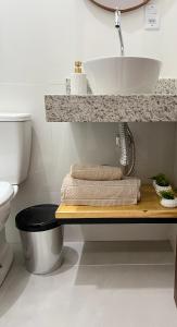 a bathroom with a sink and towels on a shelf at Flat com ar e varanda com linda vista para o Ibituruna - Véu de Noiva 204 in Governador Valadares