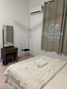 a bed in a room with a television and a sign at Qameela Mawar Homestay in Sandakan
