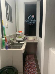 a small kitchen with a sink and a sign on the wall at Qameela Mawar Homestay in Sandakan