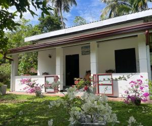 a small white house with pink flowers in the yard at Chaaya Cottage in Bentota