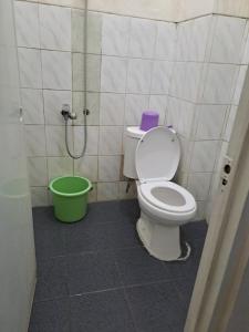 a bathroom with a toilet and a green bucket at Merapi Hotel Backpacker in Yogyakarta