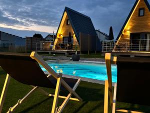 a chair next to a swimming pool in front of a house at Lady Tipi 3 avec bain nordique et piscine in Saint-Utin +10 photos