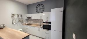 a kitchen with white cabinets and a clock on the wall at Apartament Magnolia in Nysa +2 photos