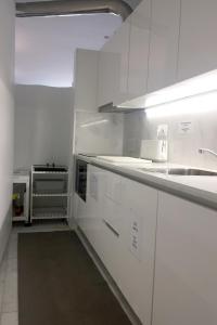 a white kitchen with white cabinets and a sink at Signature Guesthouse 2 in Porto
