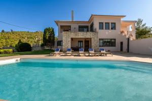 a villa with a swimming pool in front of a house at Villa Natura in Kalamos