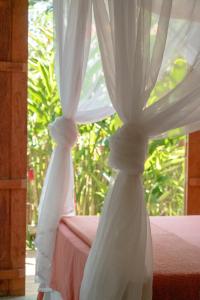 two white curtains on a bed in a room at Casa Canoa - Praia de Algodões in Marau