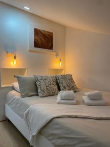 a bedroom with a large white bed with two pillows at Wood Essence Apartment - Cozy Balcony in Coimbra