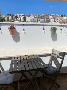 a wooden bench sitting on a balcony with a table and lights at Wood Essence Apartment - Cozy Balcony in Coimbra