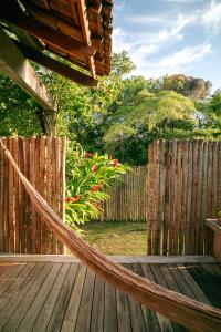 a hammock on a deck with a wooden fence at Casa Canoa - Praia de Algodões in Marau