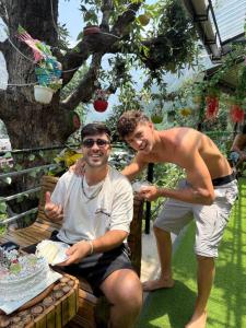 Dos hombres están de pie junto a una mesa con un pastel. en The Hilltop Kasol, en Kasol