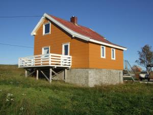 ein kleines orangefarbenes Haus mit Veranda auf einem Feld in der Unterkunft Bogstrand, Dverbergveien 11, 8485 Dverberg in Dverberg