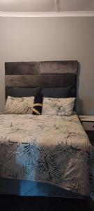 a bed with a headboard and pillows in a bedroom at Green Escape Cottage Guesthouse in Albert Falls