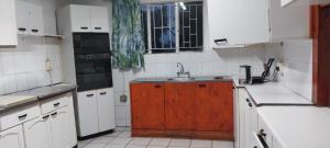 a kitchen with a sink and a wooden cabinet at Green Escape Cottage Guesthouse in Albert Falls