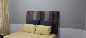a bed with a wooden headboard and two pillows at Green Escape Cottage Guesthouse in Albert Falls +8 photos