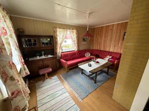ein Wohnzimmer mit einem roten Sofa und einem Tisch in der Unterkunft Bogstrand, Dverbergveien 11, 8485 Dverberg in Dverberg