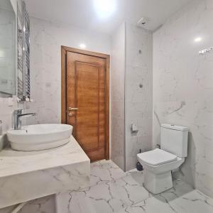 a white bathroom with a toilet and a sink at Panoramic #1 Sea Mountain View 1BR apartment Living Room, Balcony, Kitchen in Batumi +8 photos
