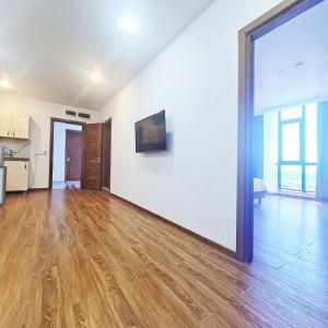 an empty living room with wooden floors and a large window at Panoramic #1 Sea Mountain View 1BR apartment Living Room, Balcony, Kitchen in Batumi
